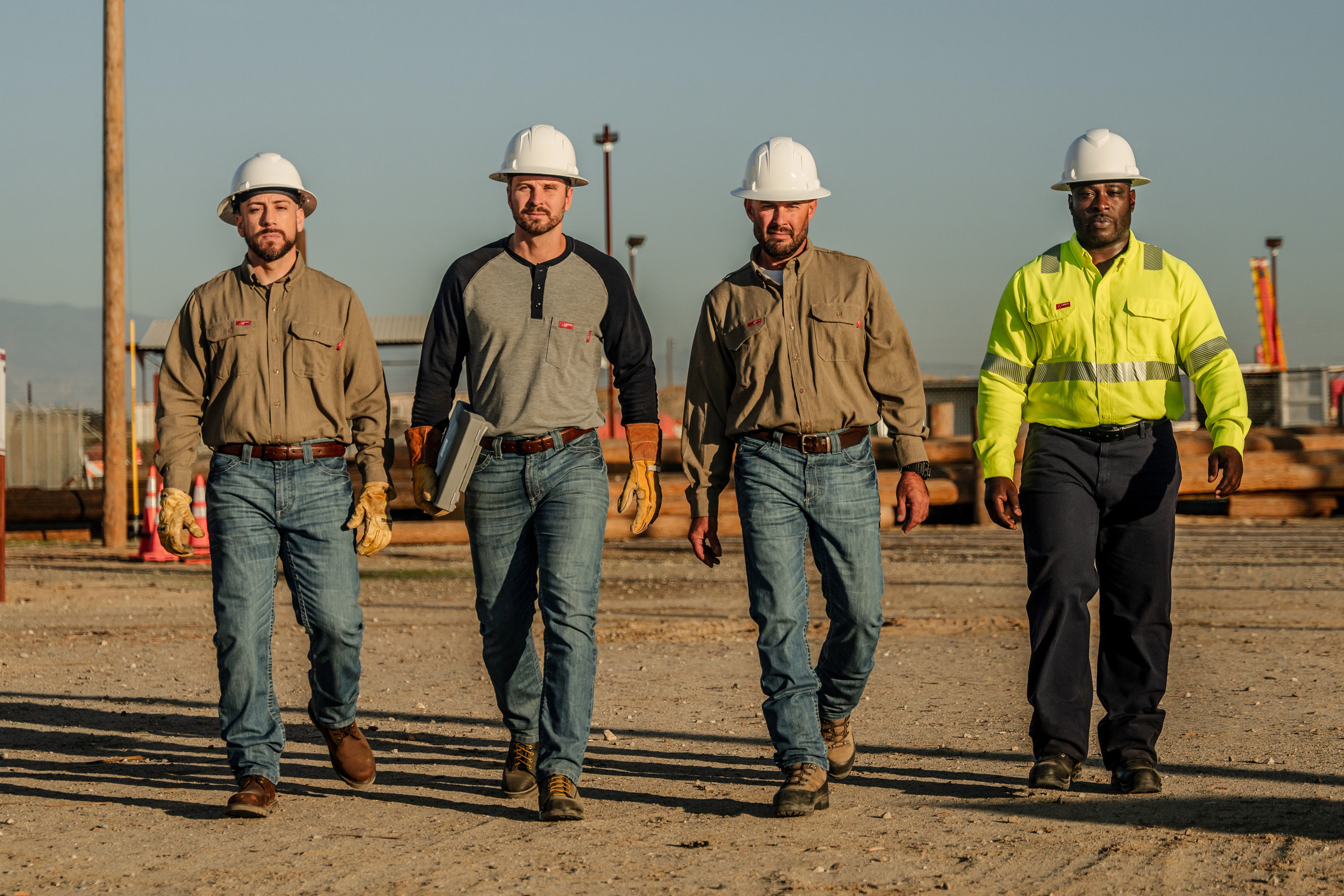 Four workers in LAPCO FR workwear walking on a work site.